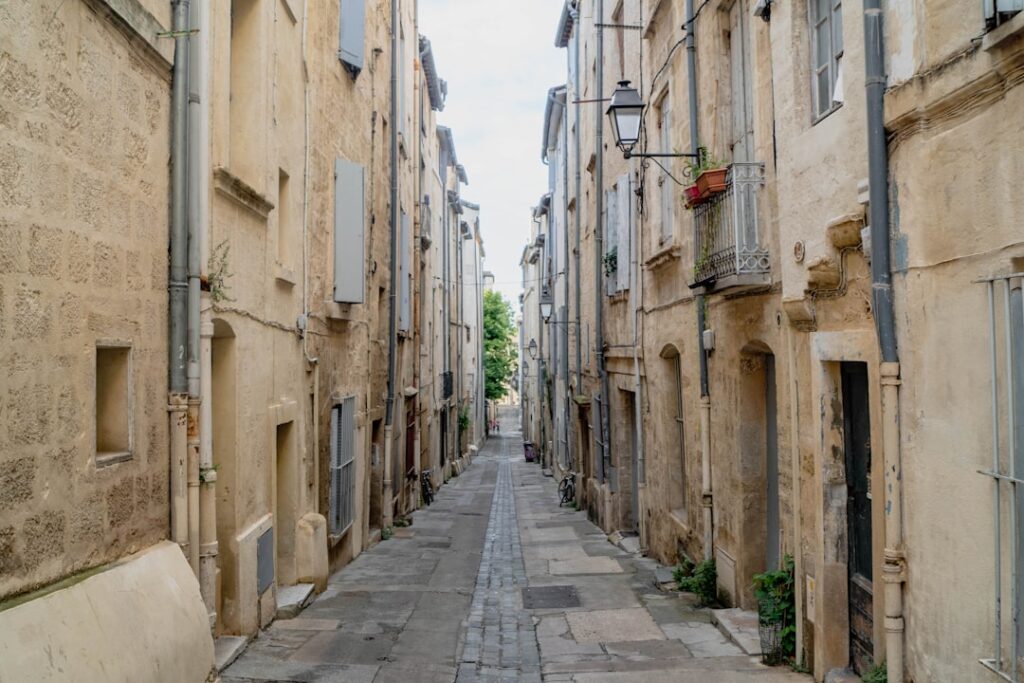 gray-concrete-pathway-between-beige-concrete-buildings-during-daytime-3hwzrwd7qwq